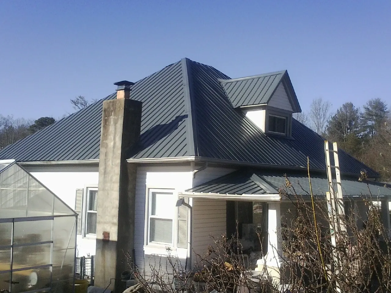 Dark blue standing seam metal roof on a white farmhouse with dormer — Slate & Tile Roof Repair by Roofing Brothers in Chino Hills