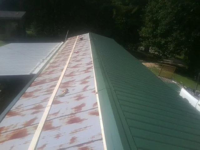Old rusted panels beside newly installed green metal roofing — Wind Damage Roof Repair by Roofing Brothers in Chino Hills