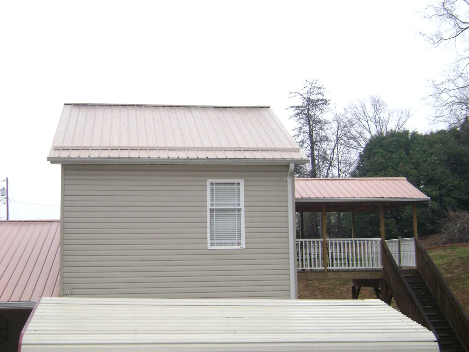Tan metal roofs on a two story addition and attached porch, from a Roof Replacement job in Chino Hills