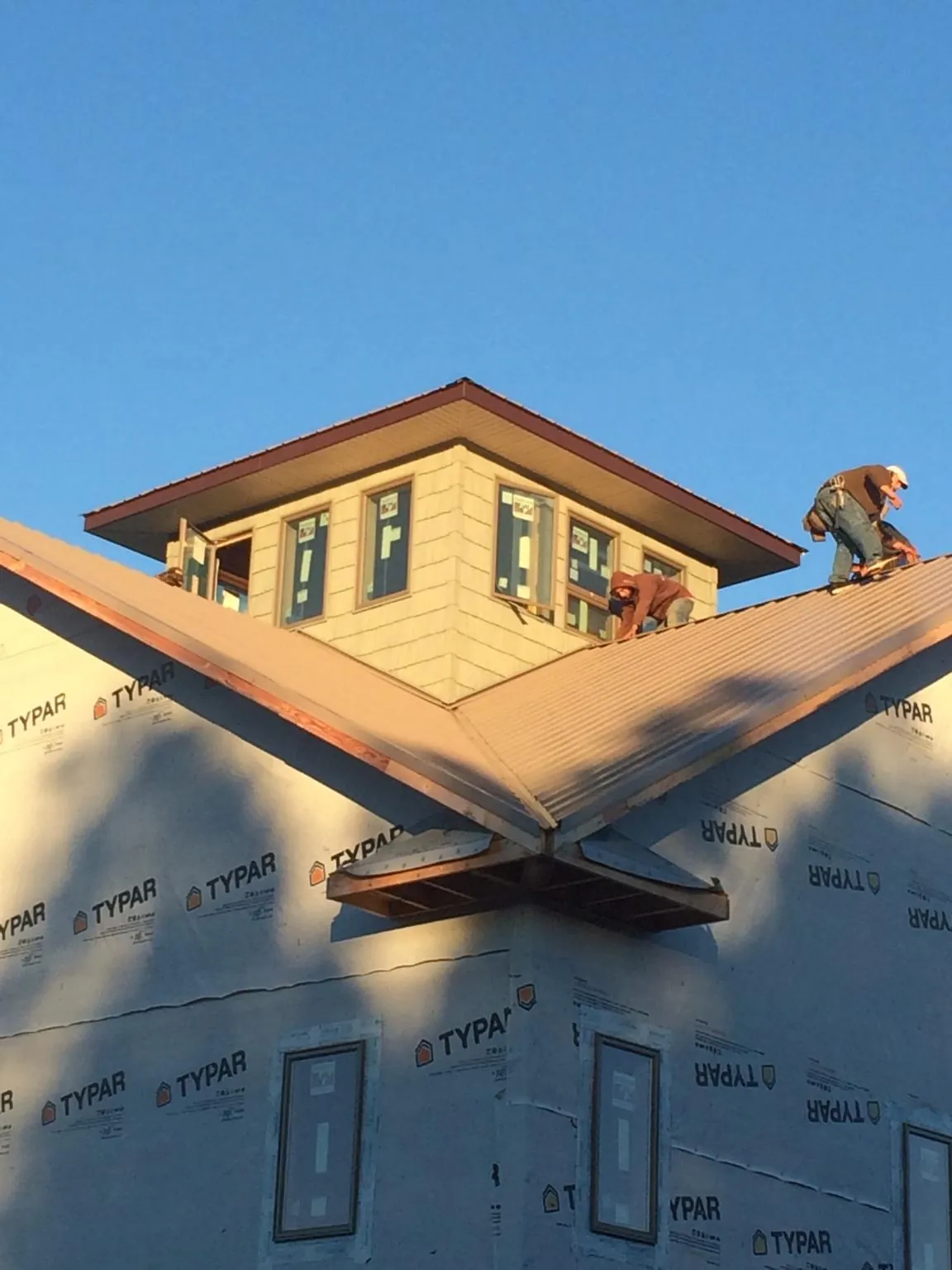 Roofers working around a rooftop cupola on a new metal roof at sunset — Roof Waterproofing in Chino Hills by Roofing Brothers
